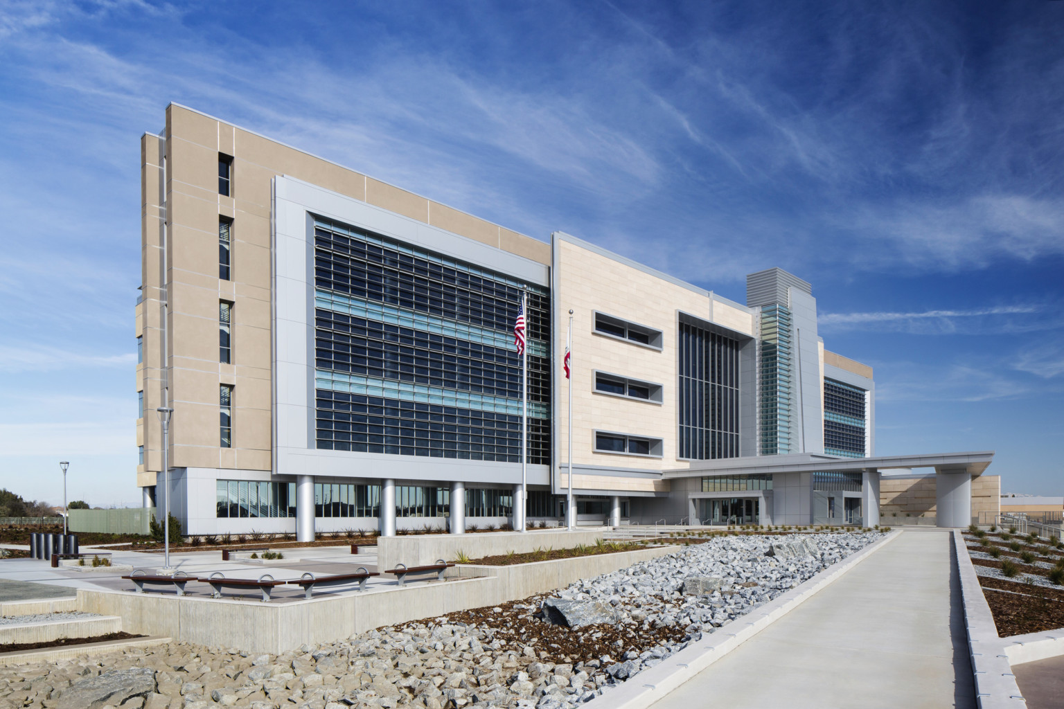 Kings County Courthouse exterior view. A 4 story building with stone and glass facade. 2 flags stand in front of the building