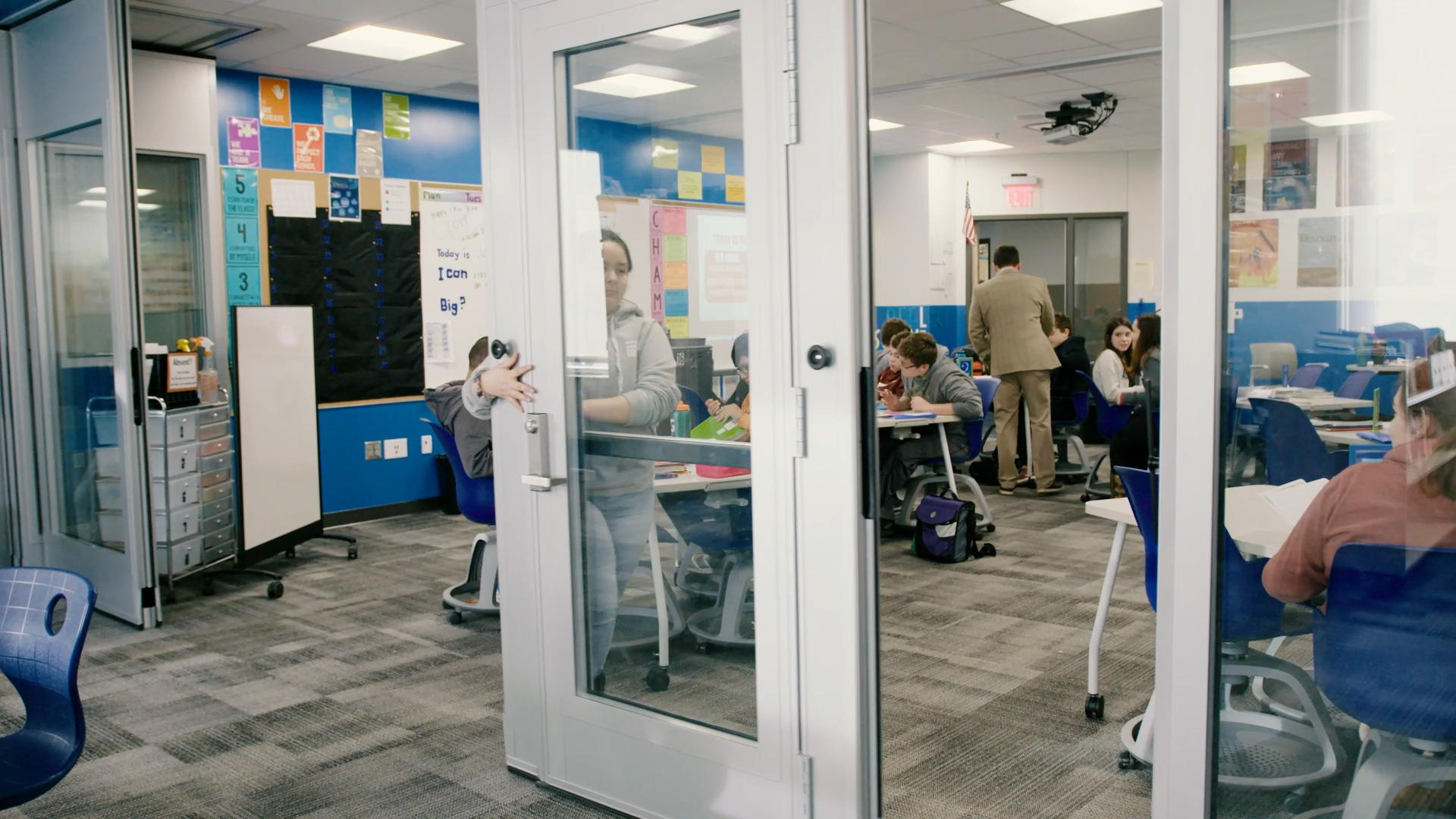 student pushing a glass folding door closed to open up a classroom for collaboration