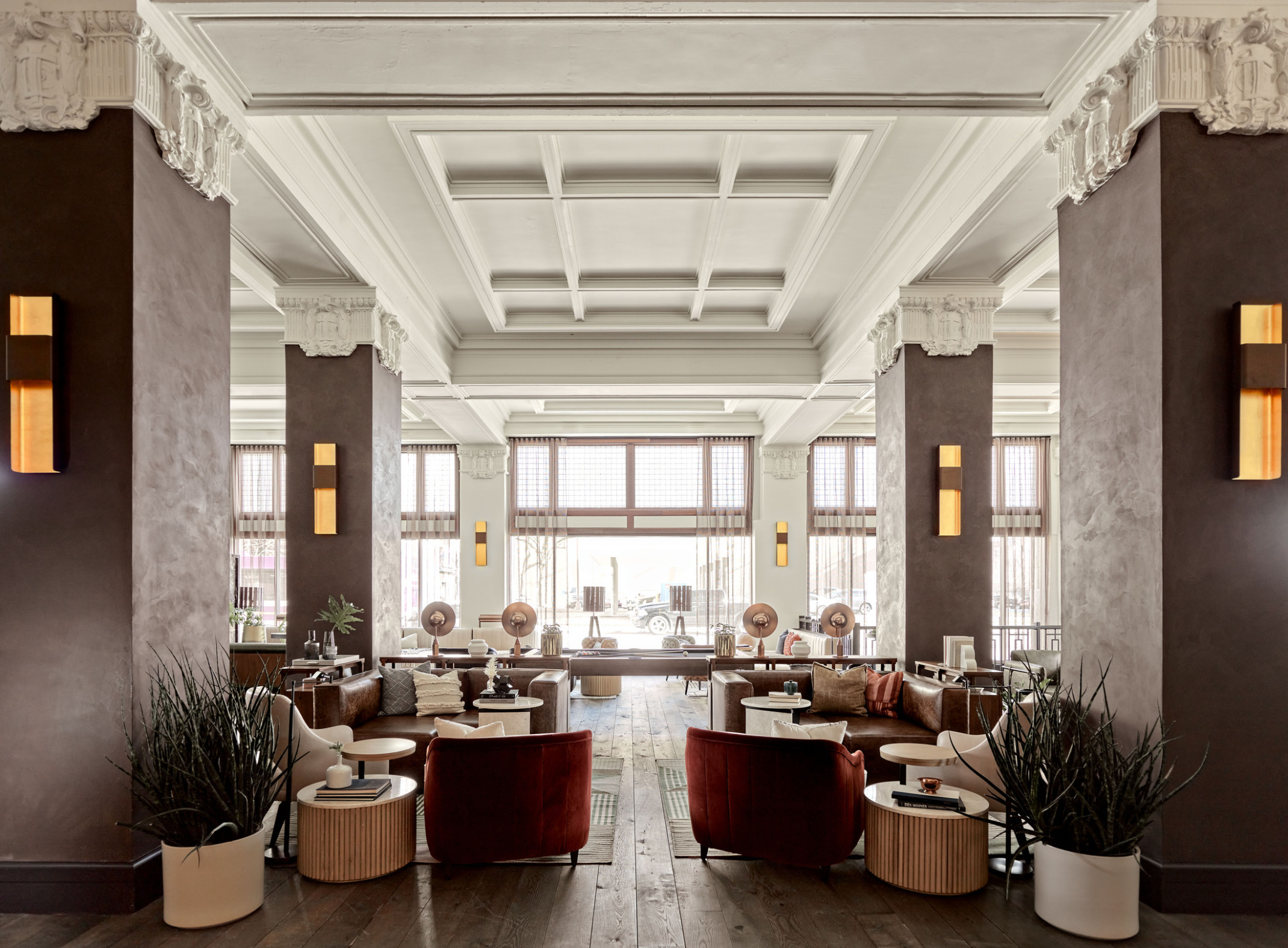 Seating area in the with wood pillars and white stone capitals in white room with recessed ceiling details. Pool table center
