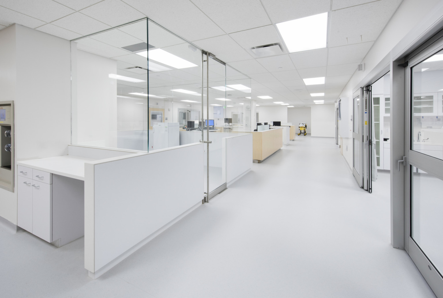 Bright white emergency room nurses stations opposite patient rooms have glass walls for visibility