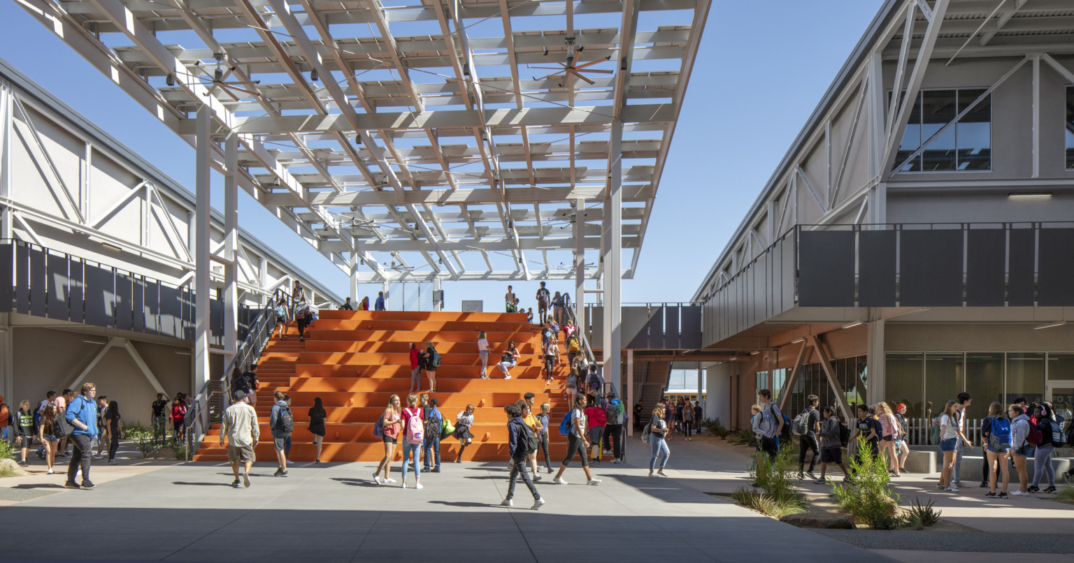 Looking out to students on orange bleacher steps partially cover by a solar canopy