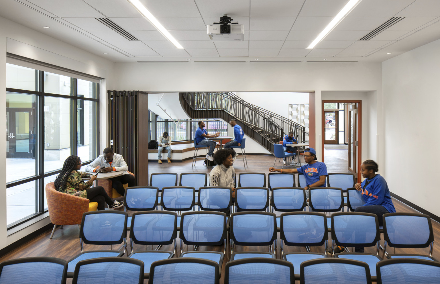 Off the main lobby with high tables and chairs, a room with flexible wall and chairs facing forward. More seats near windows