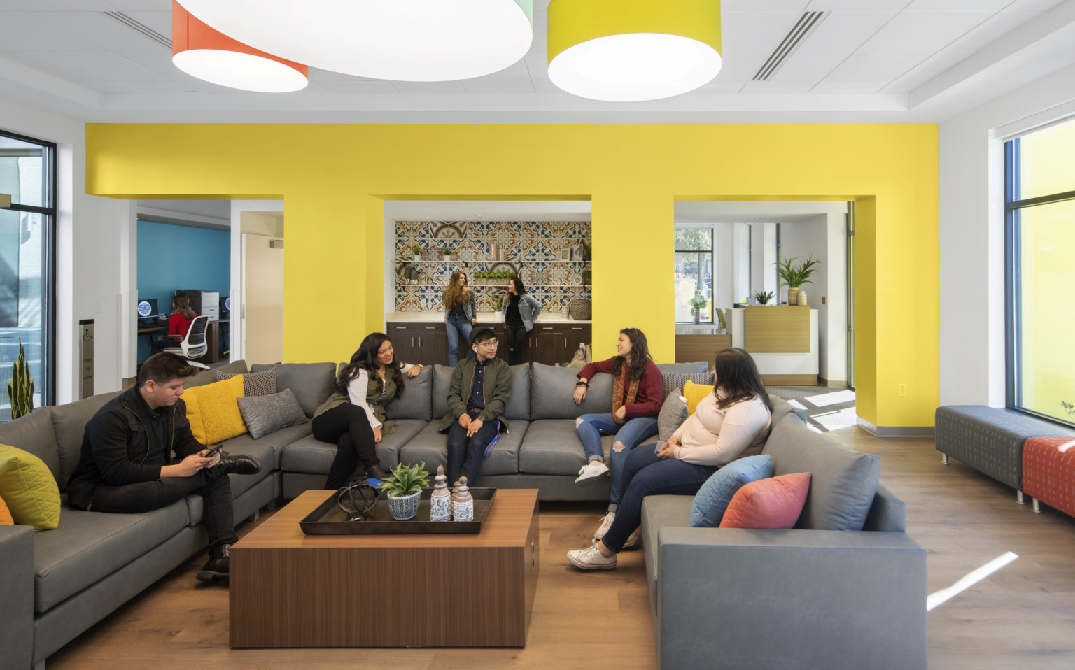 Yellow seating area off entry with large U shaped sectional and coffee table. Recessed counter in center of wall with tiles