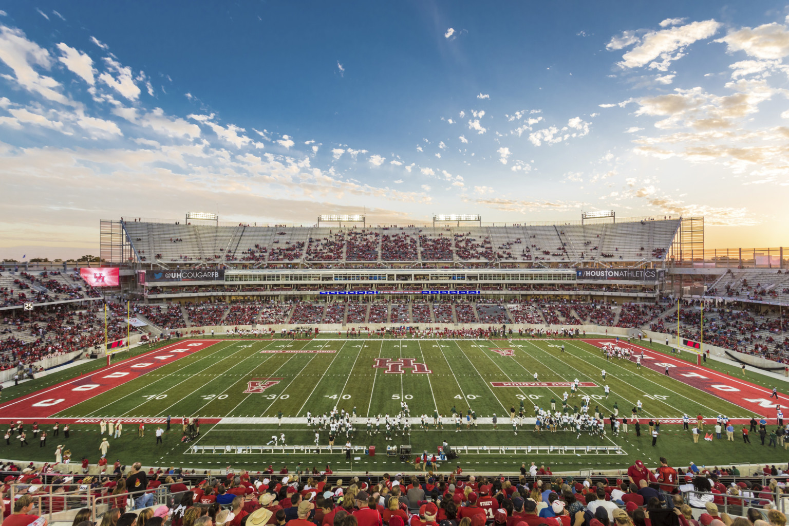 View of football field from upper deck seating at 50 yard line. Red end zones with Houston Cougars written across them