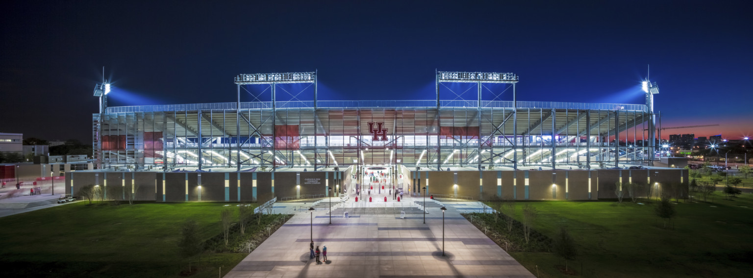 TDECU Stadium at University of Houston front entrance illuminated at night. Red UH logo over entry