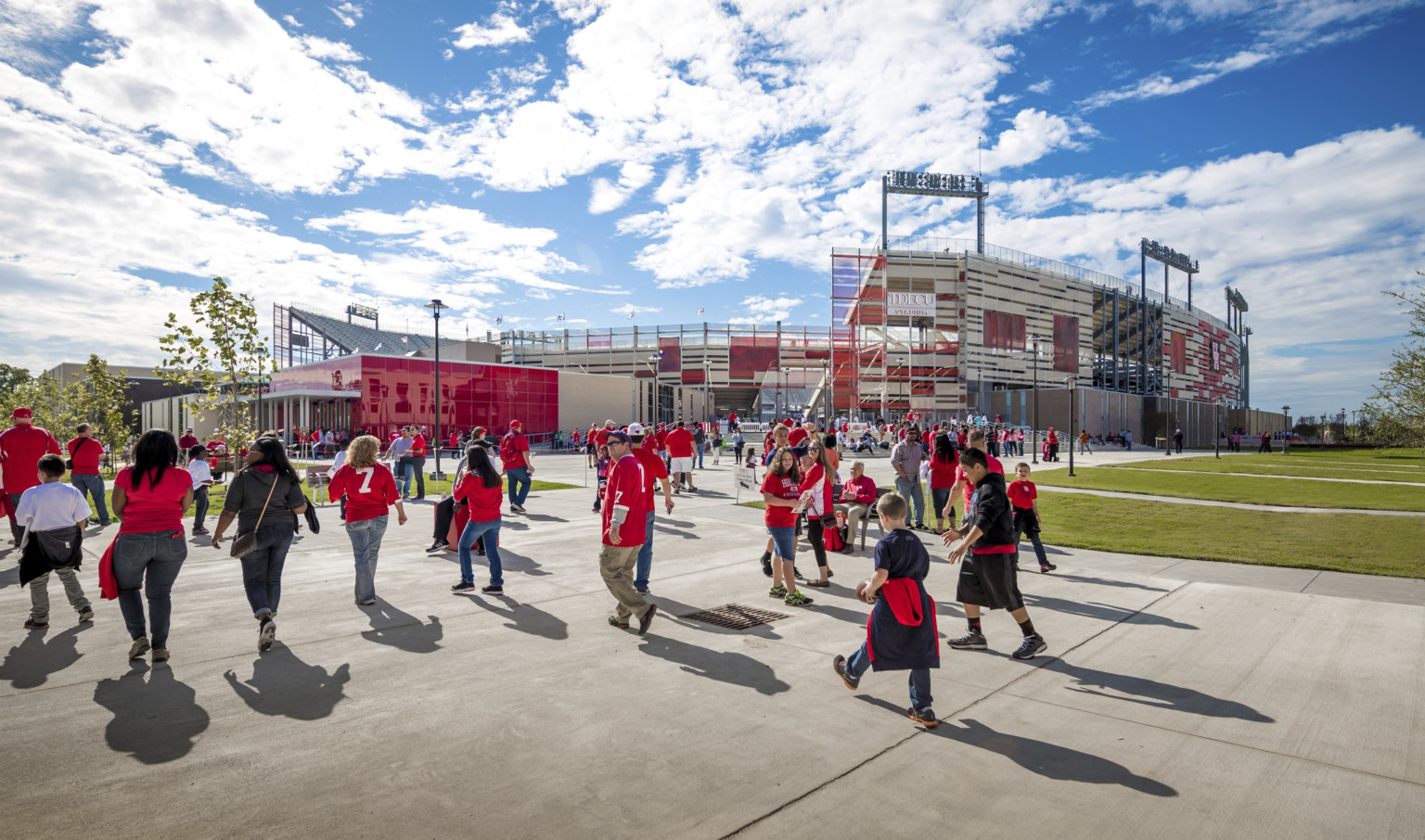 Corner view of a stadium entrance below gap in upper seating bowl. Red and white building extends off to left of entrance