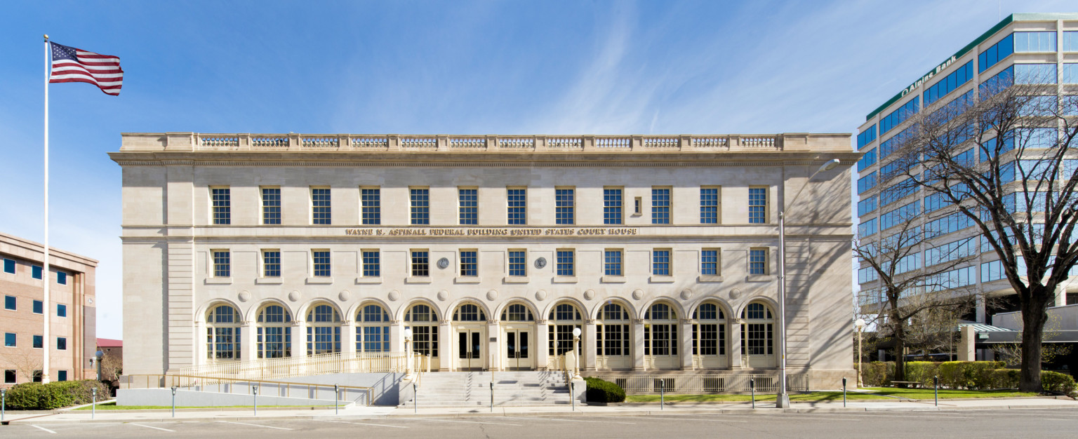 Front entry of a three story limestone Italian Renaissance Revival style building with ramp and gold toned railing at left