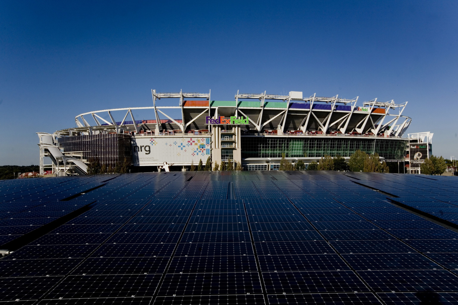 FedExField, home of the Washington Commanders, with large-scale solar array before stadium with LED display, glass facade