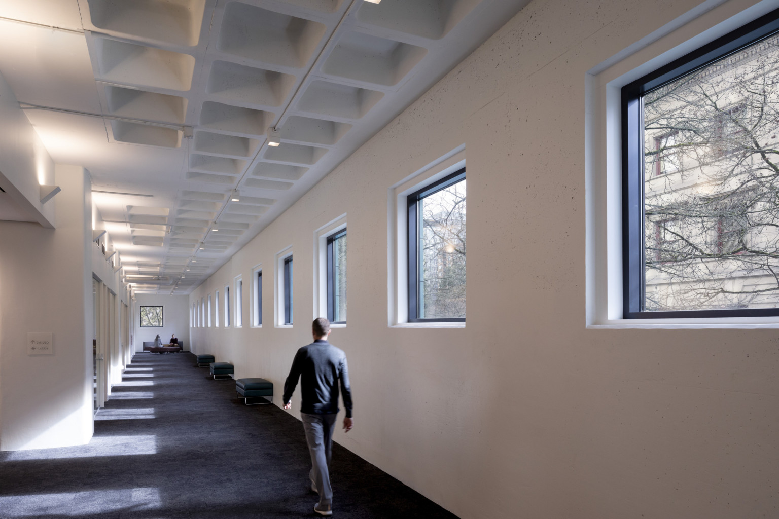 Tall white waffle slab ceiling over a perimeter corridor lined with square windows, portland building renovation, restoration, postmodern architecture, michael graves architecture