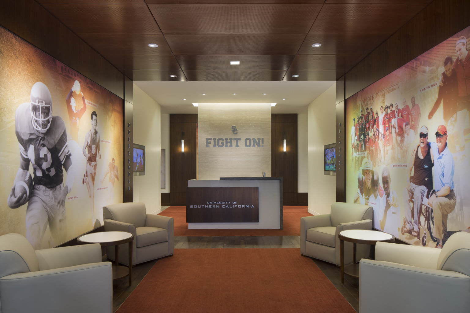 Reception desk with University of Southern California sign at the end of a hallway lined with murals and armchairs