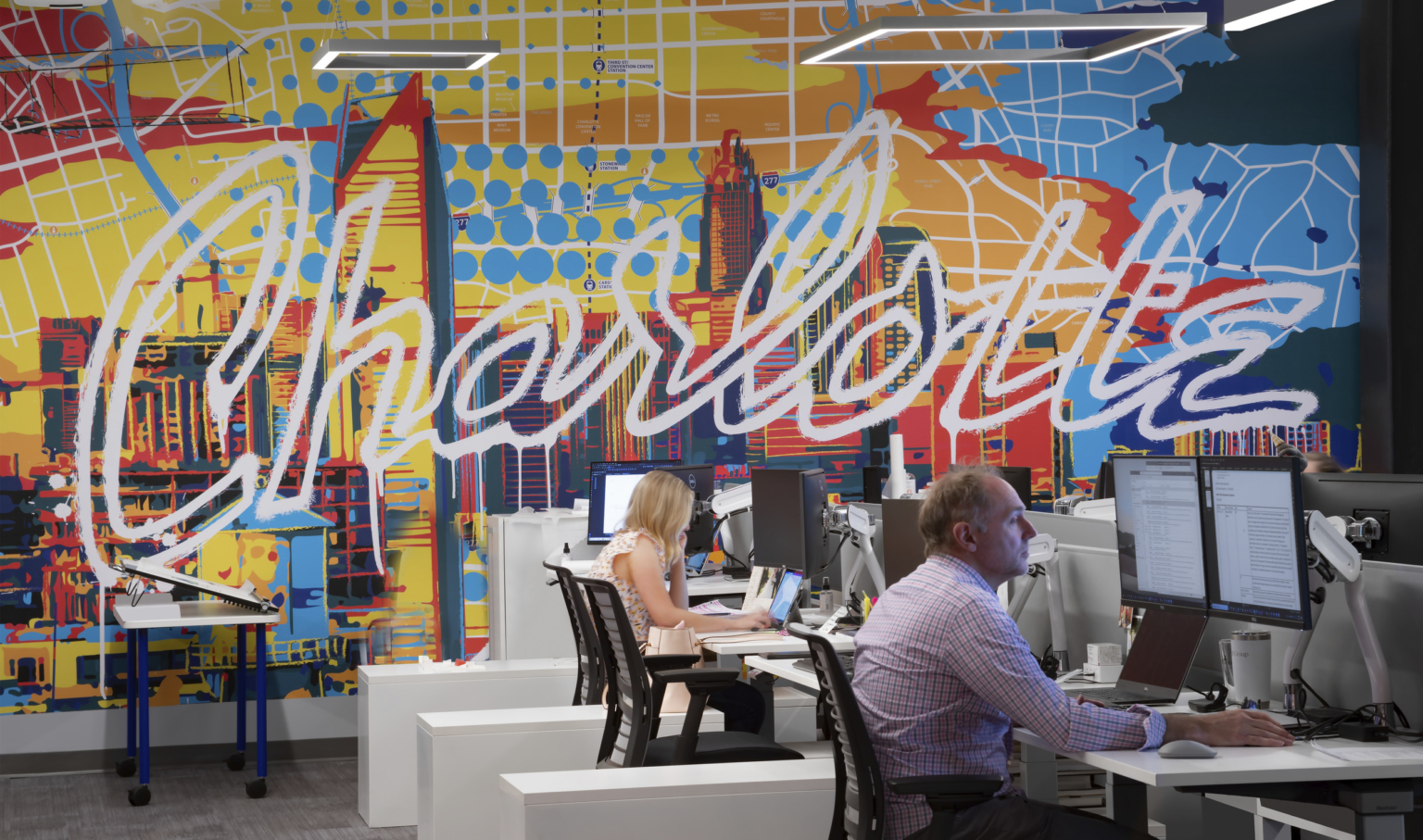 Row of desks in front of multicolor mural reading Charlotte in white