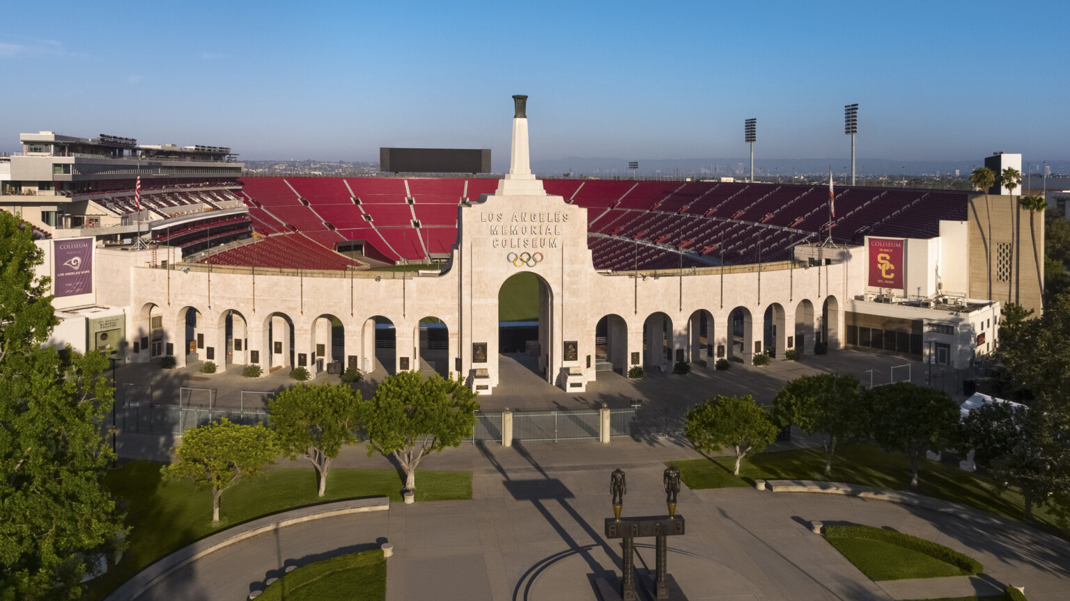 Front of stadium with Robert Graham sculpture Olympic Gateway at center of round plaza with greenery and arched entryway