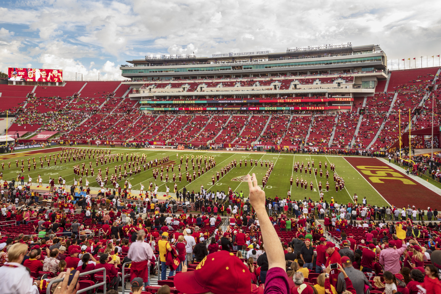 Students form letters USC on football field surrounded by red bleachers. Box seating opposite with LED ribbon displays