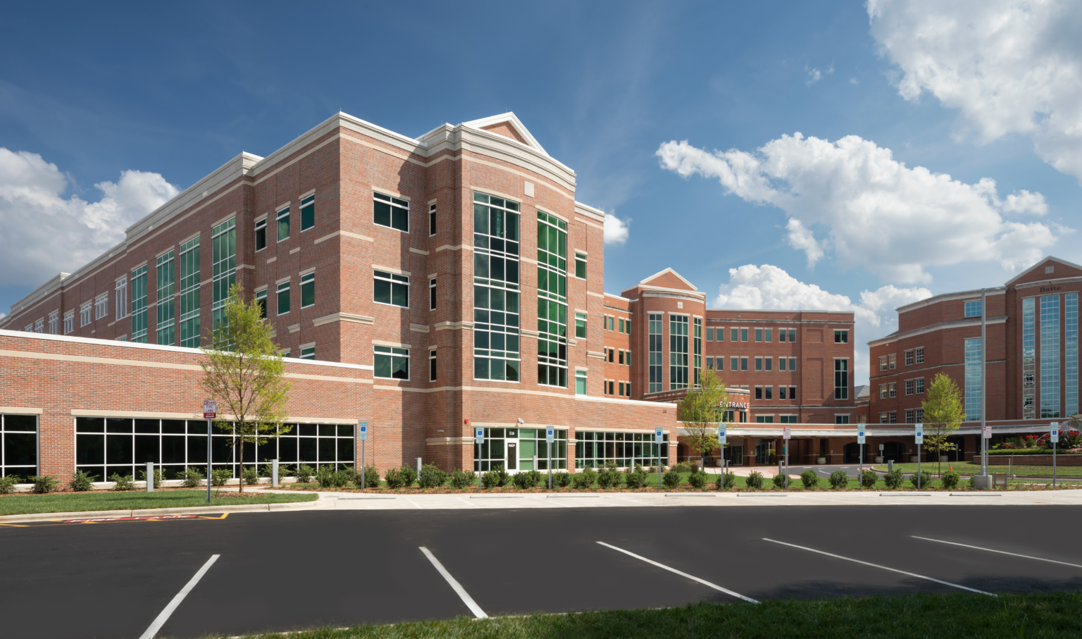 Exterior view from parking lot of a warm brick building in classic form and green-tinted windows