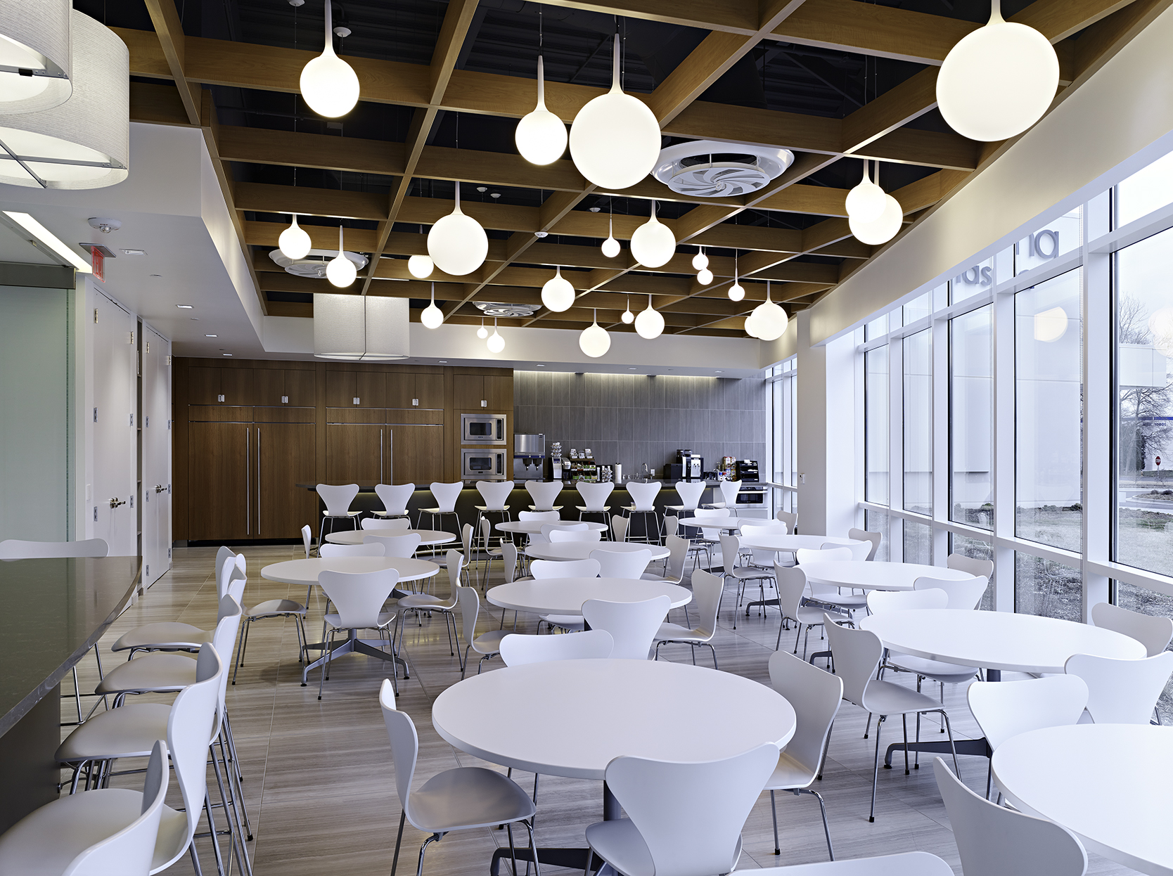 dining space with white tables and chairs, wood panel ceiling, and white round bulb pendant lighting
