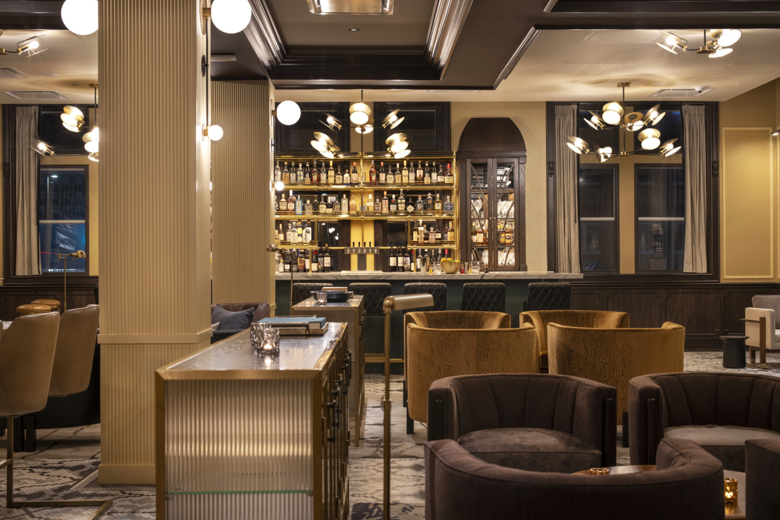 Kimpton Cottonwood Hotel lobby with velvet upholstered seating area in front of marble counter bar. Chandelier light fixtures