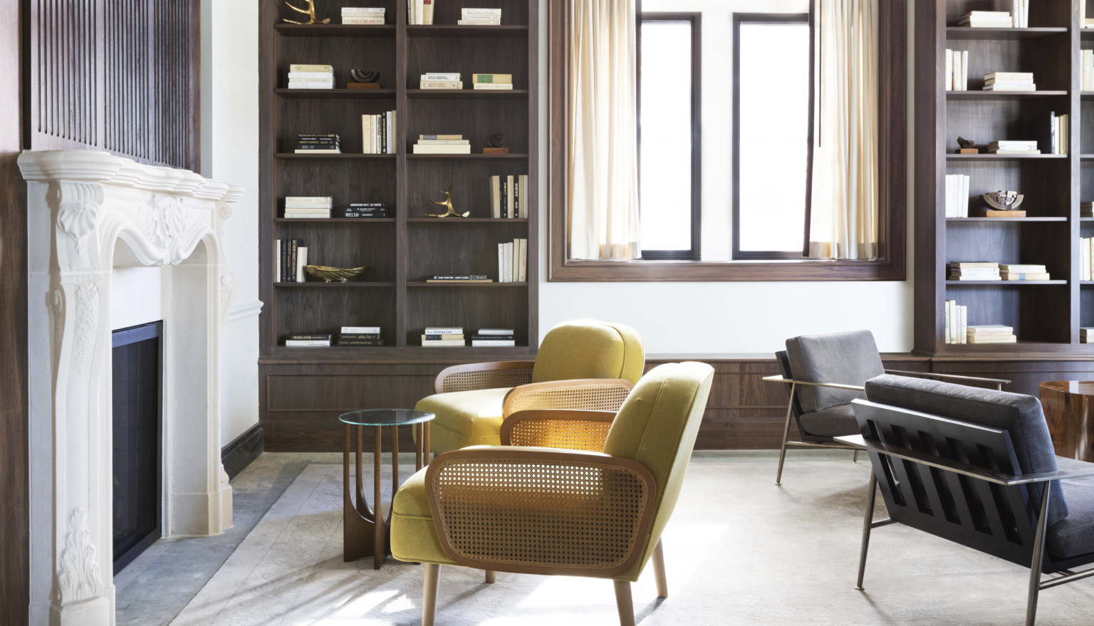 chartreuse and wicker cane chairs in front of a white fireplace and wooden bookcases