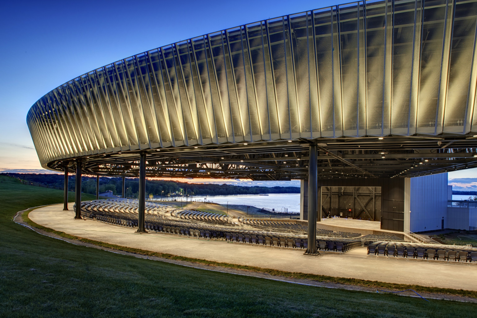Evening view of perforated and sculpted outdoor amphitheater canopy at Onondaga Lakeview Amphitheater