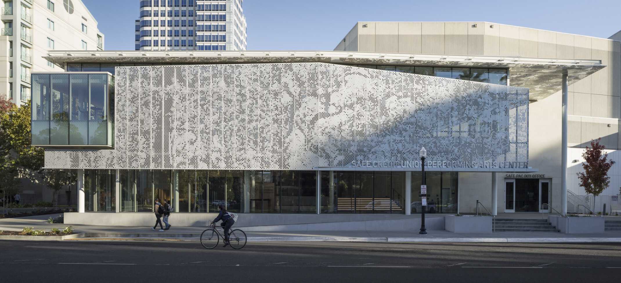 Perforated façade on a large two-story building in Sacramento. Perforated white metal scrim on the exterior shades from the sun. First floor open to the street with full glass windows.