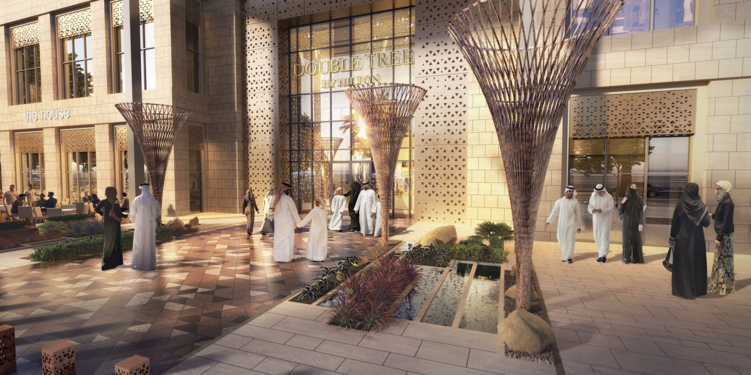 Madinah Gate, a glass and light stone mixed use building with gold accents. In front, tables with white umbrellas and chairs