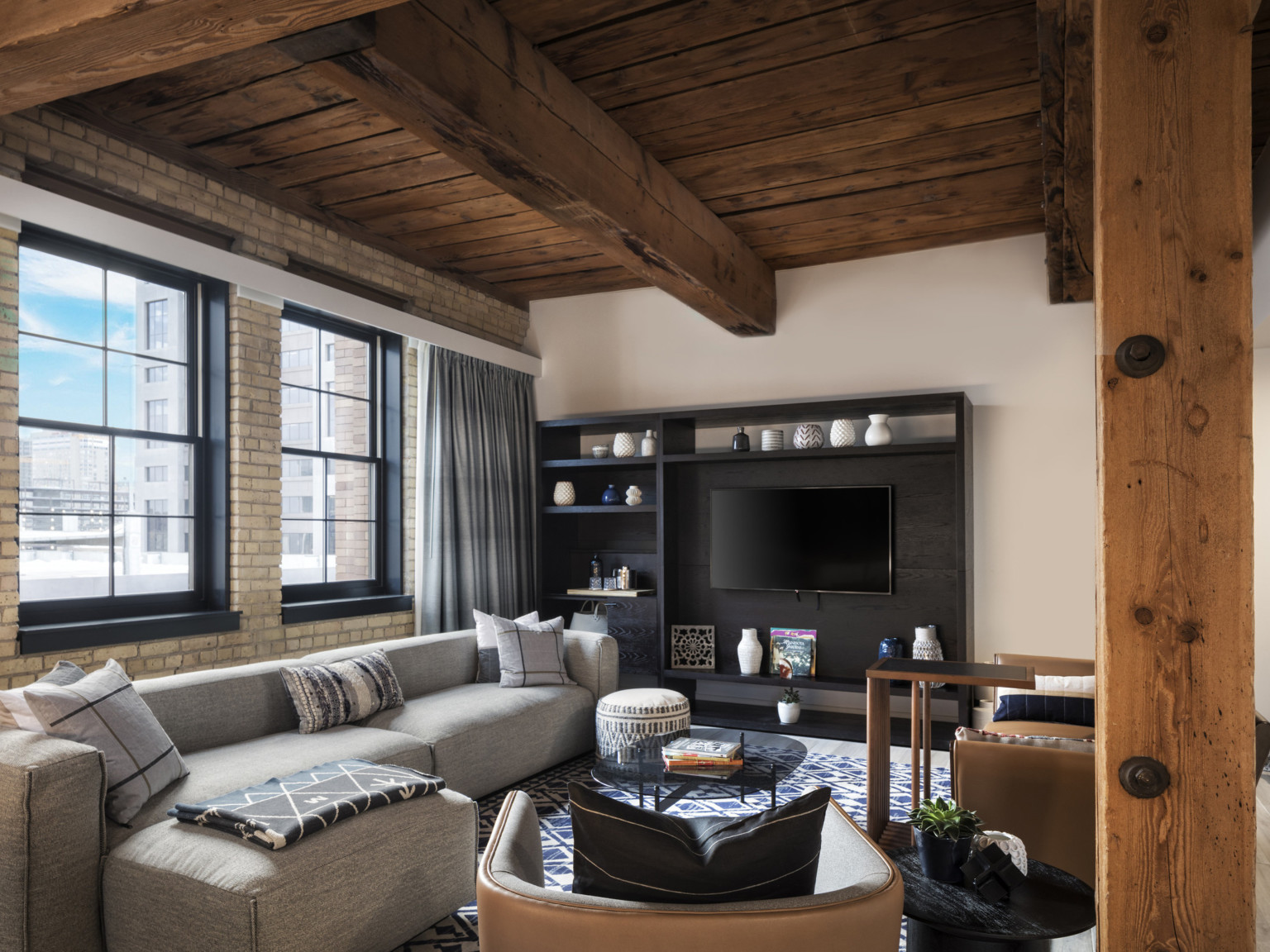 Heavy timber ceiling, beams, and columns with a gray sofa and dark wood entertainment center