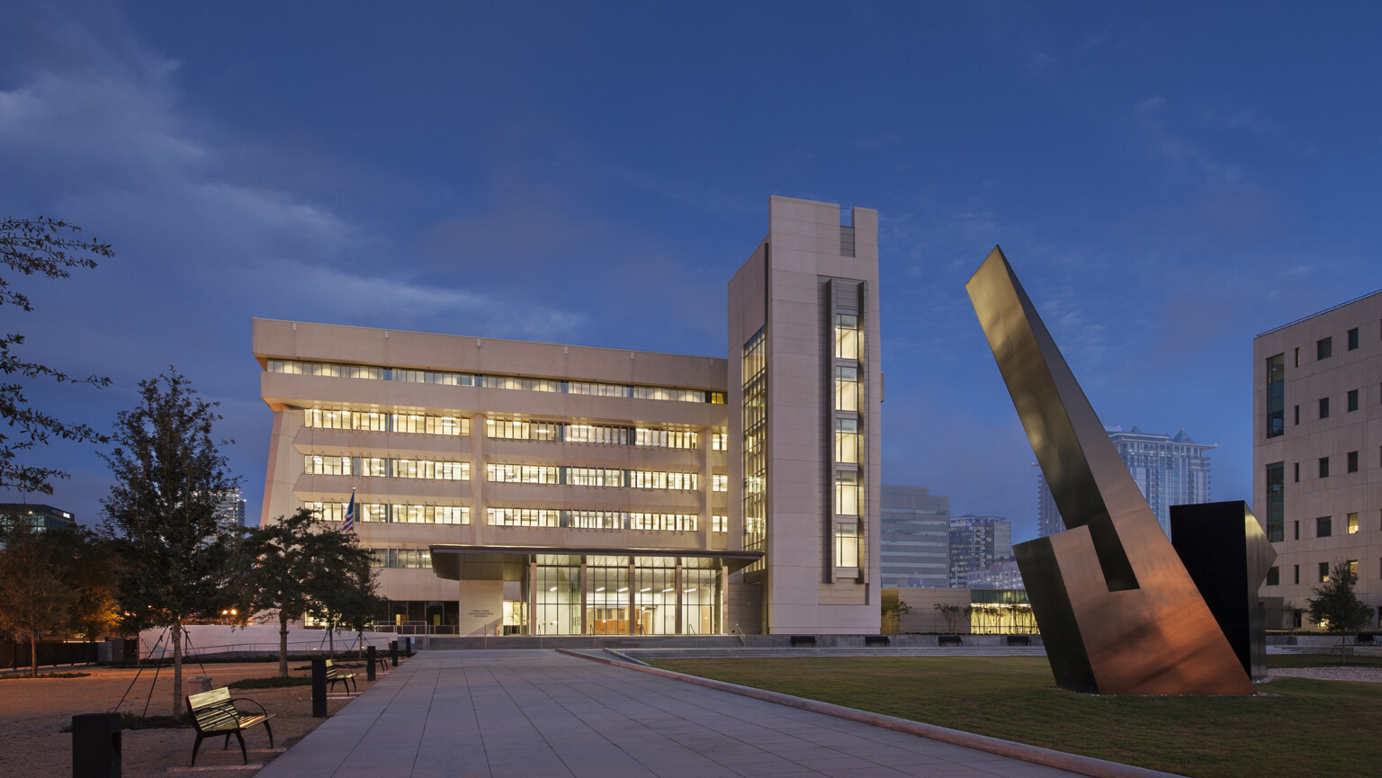 illuminated federal building at night with large sculpture on the lawn