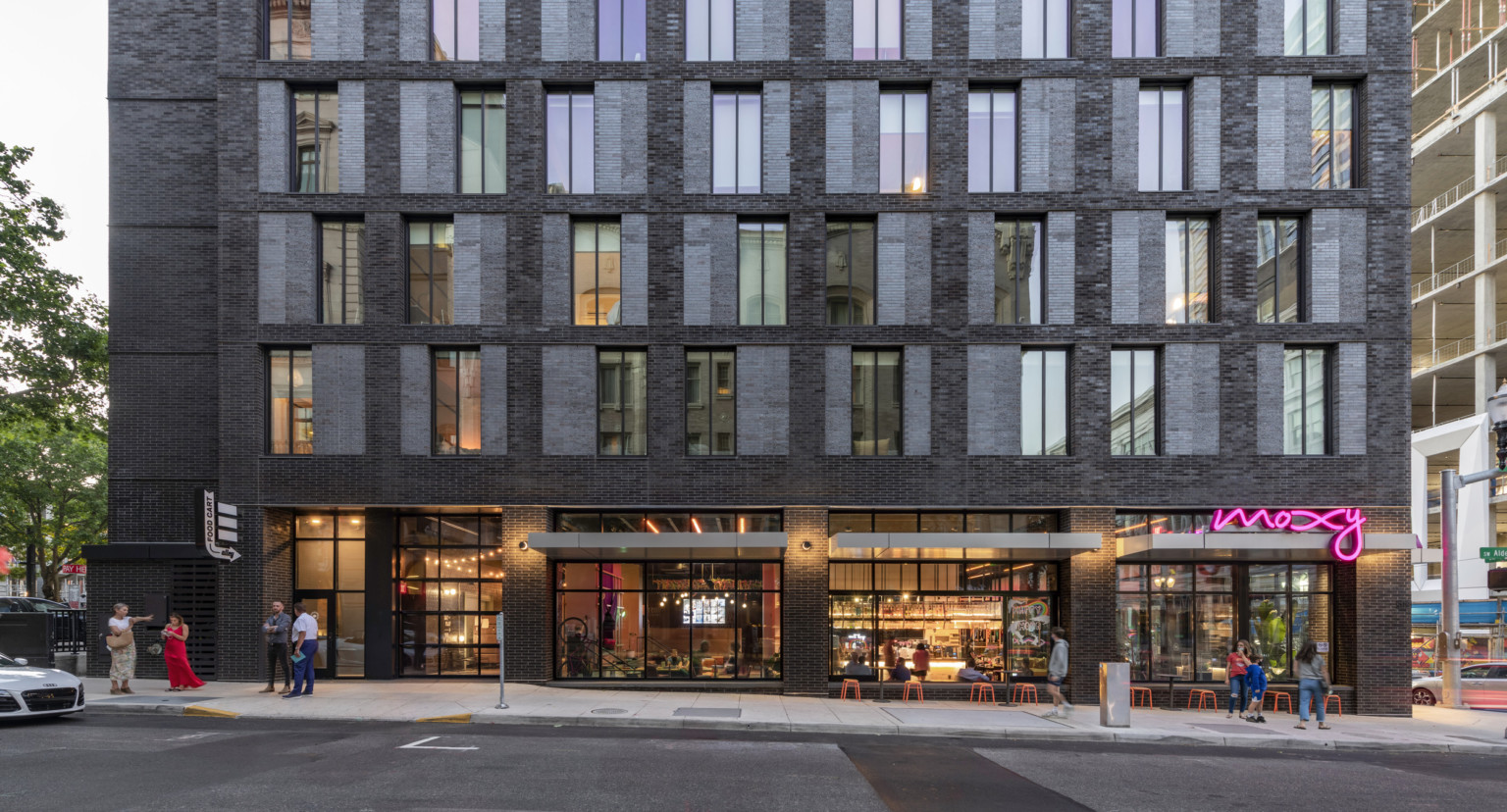 Closeup view of lobby and 1st 5 stories. Lobby has floor to ceiling windows with grey flat awnings separated by brick columns