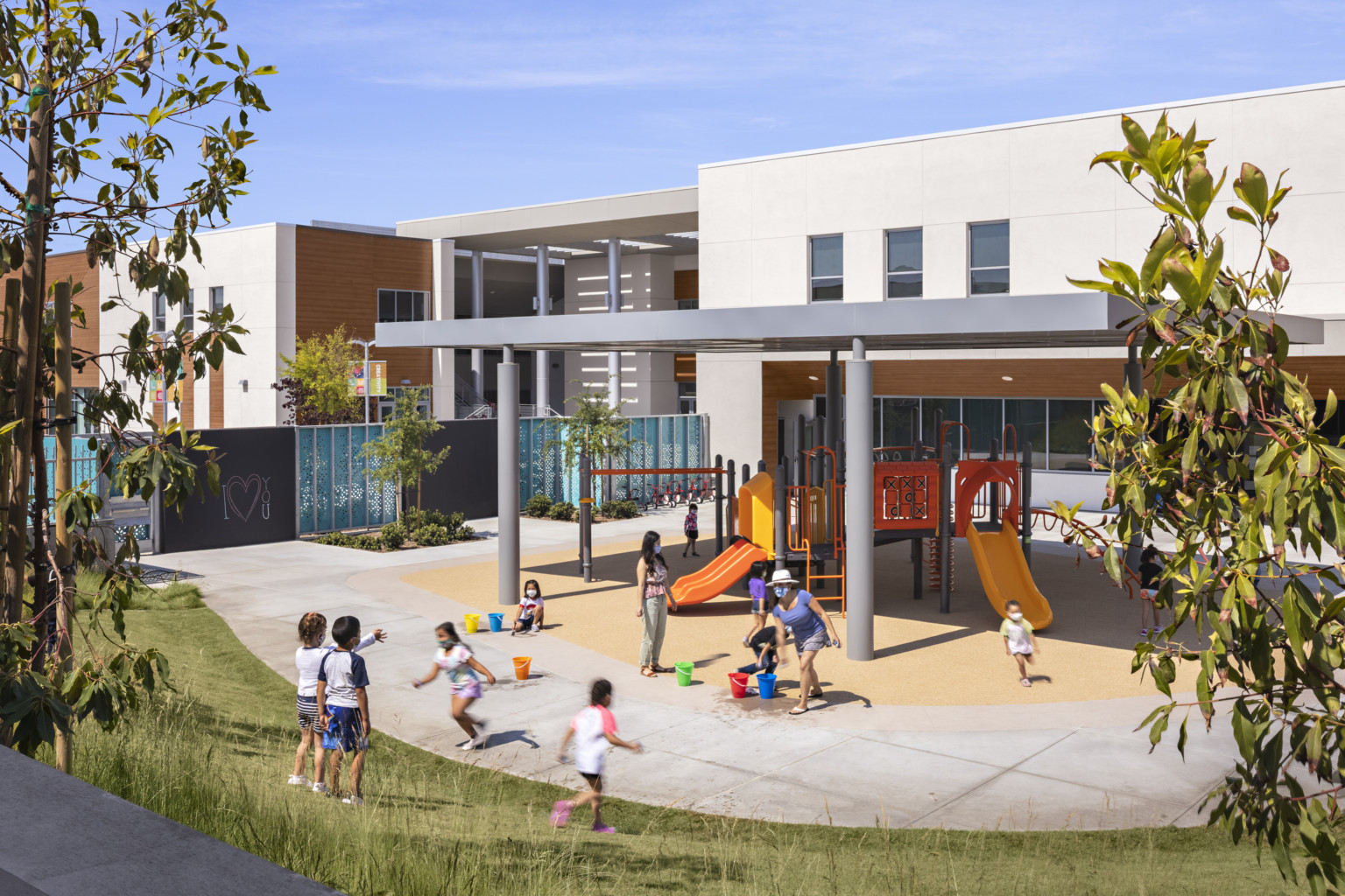 A playground shaded in a large yard with murals and chalkboards along fence and plant space