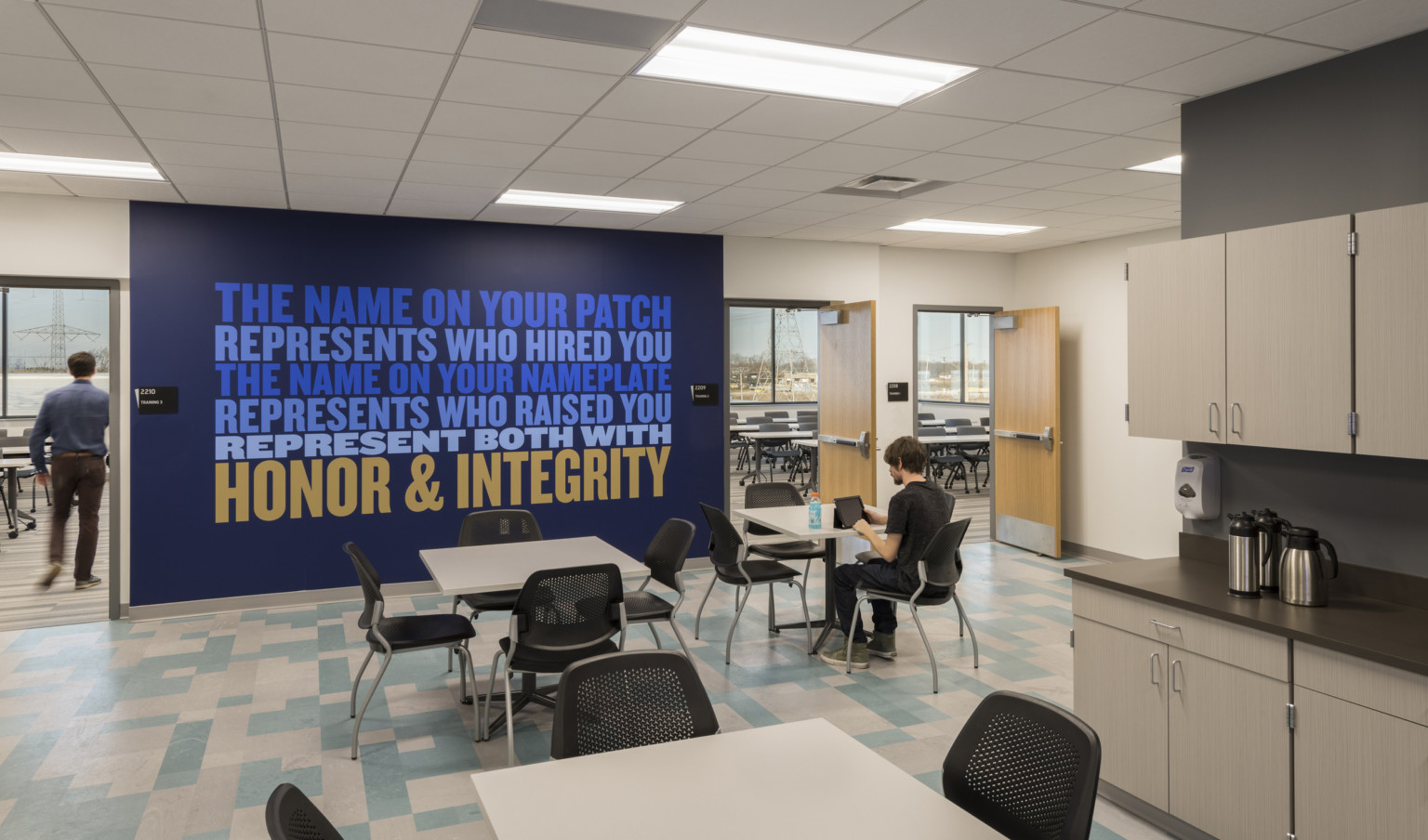 inside room with chairs and blue wall mural with blue and yellow words saying to represent the department and their name well