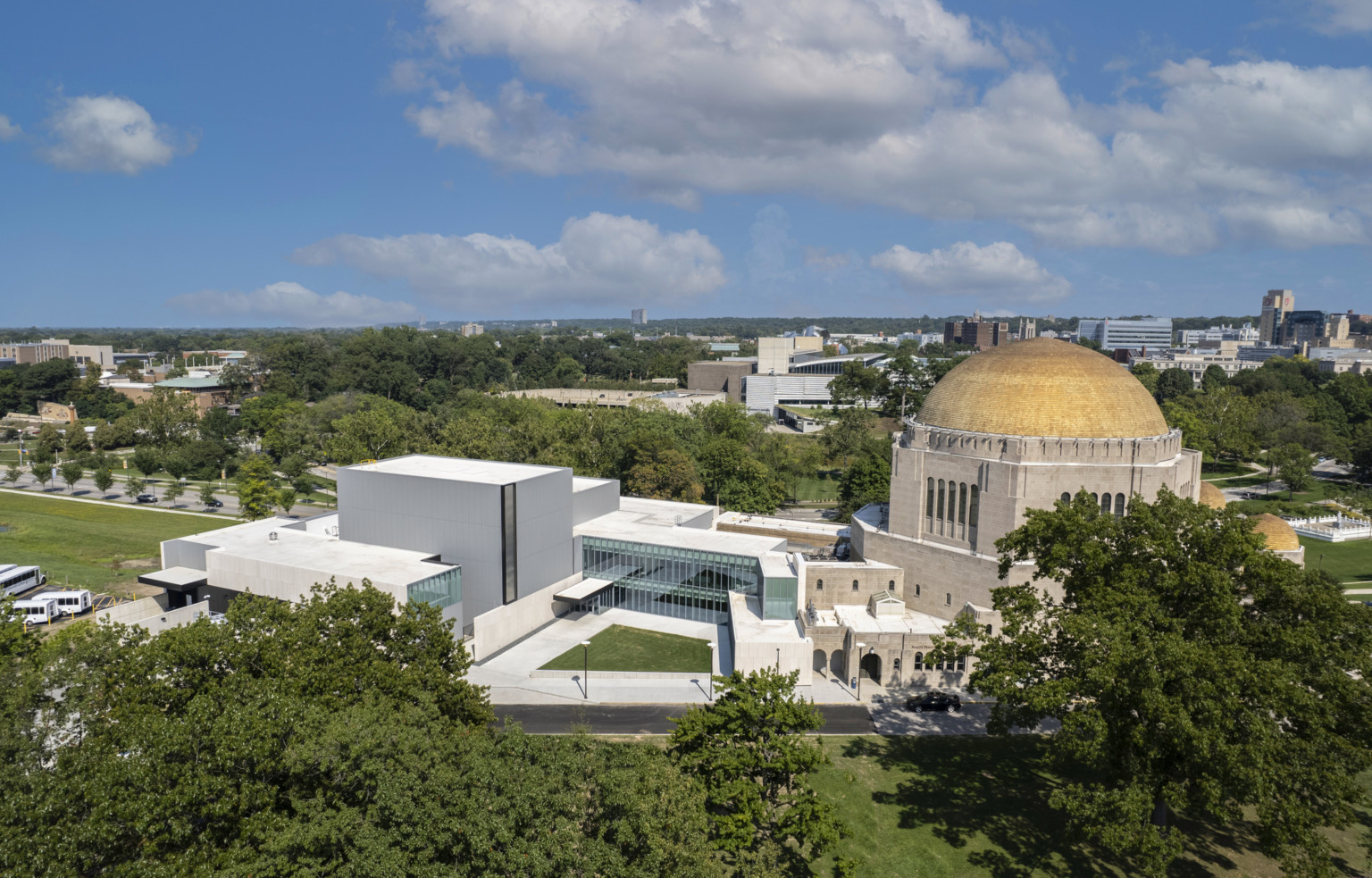 View from above of glass building connecting modern concrete building to historic building with yellow dome