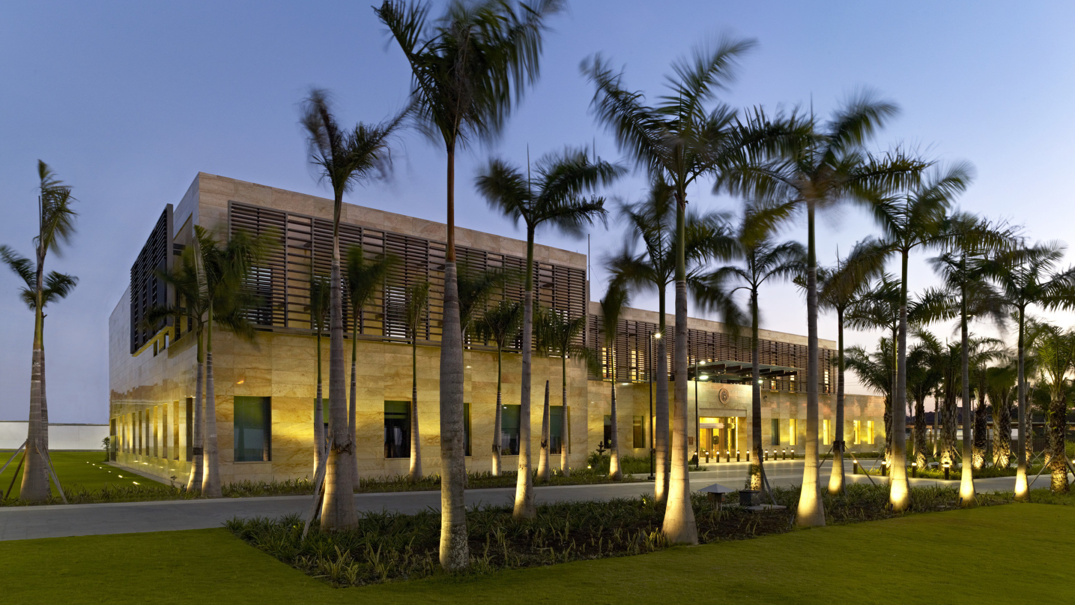 evening exterior view of US Consulate in Surabaya, Indonesia with palm trees and lighting features
