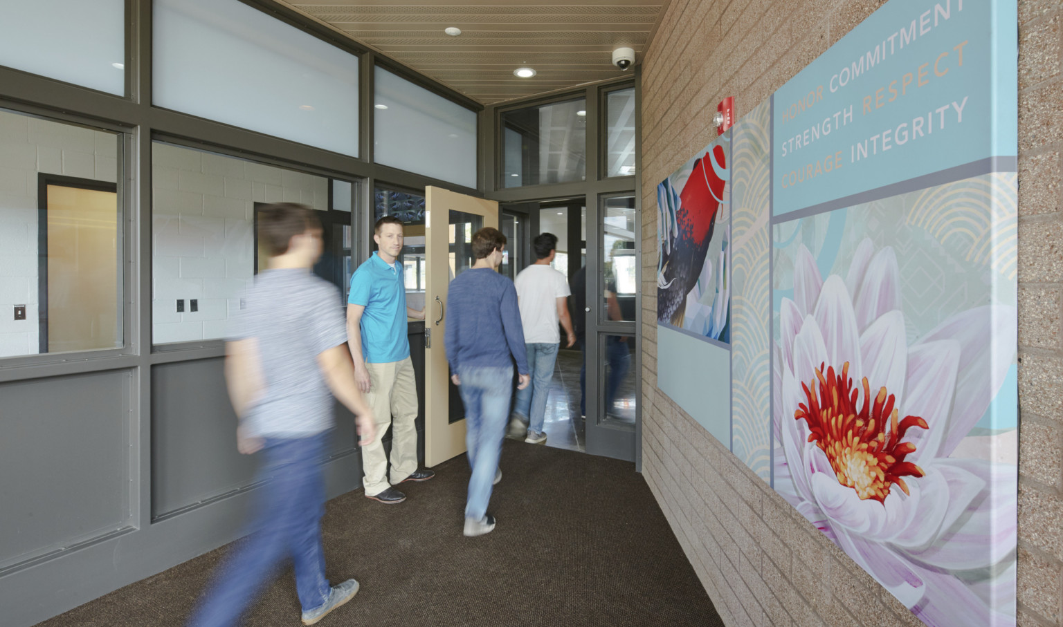 people walking through doorway inside Oregon Youth Authority MacLaren Campus with blue and red artwork on wall