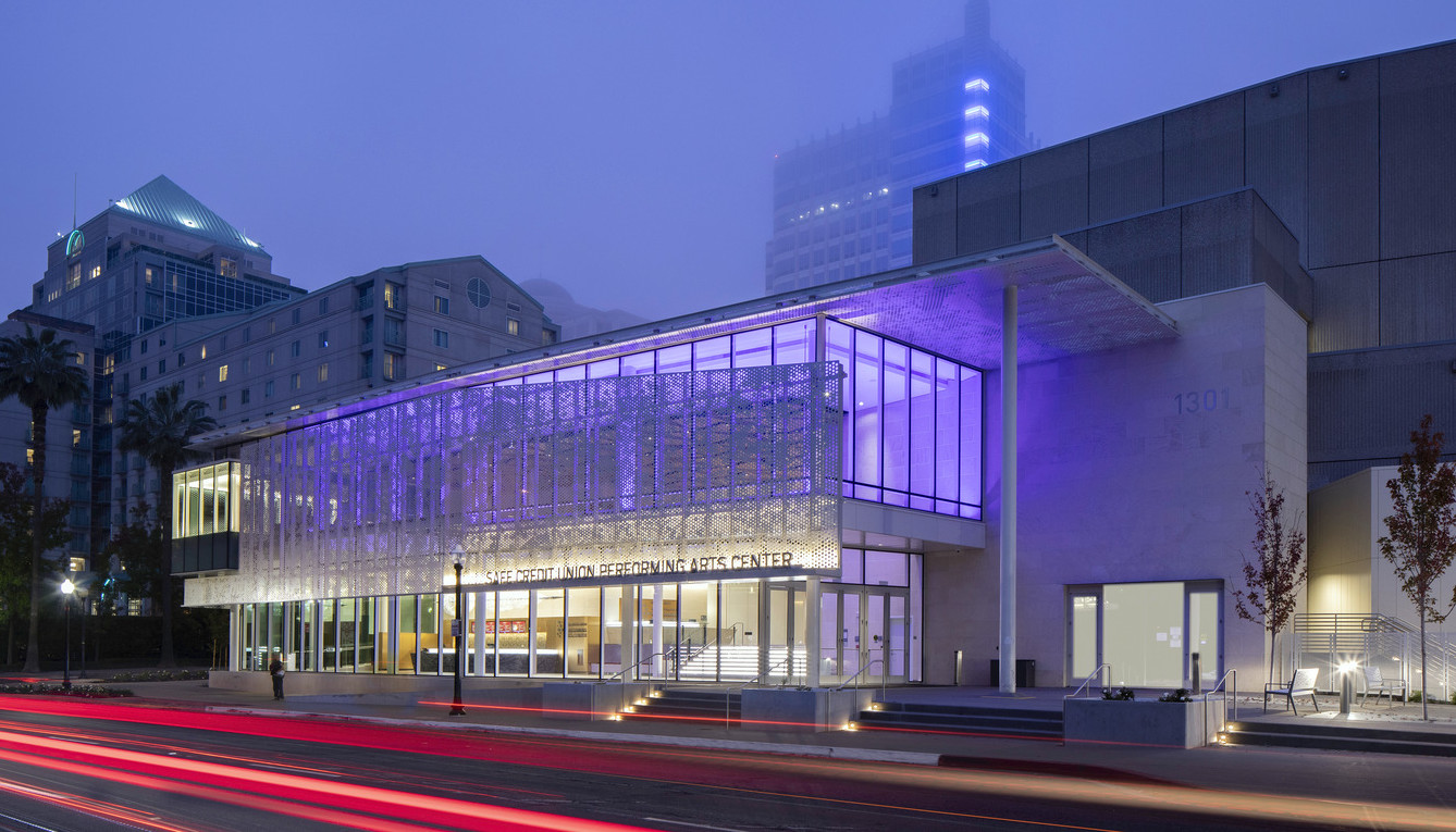 Looking from across the street at the exterior of the SAFE Credit Union Performing Arts Center in Sacramento, lit up with purple lights