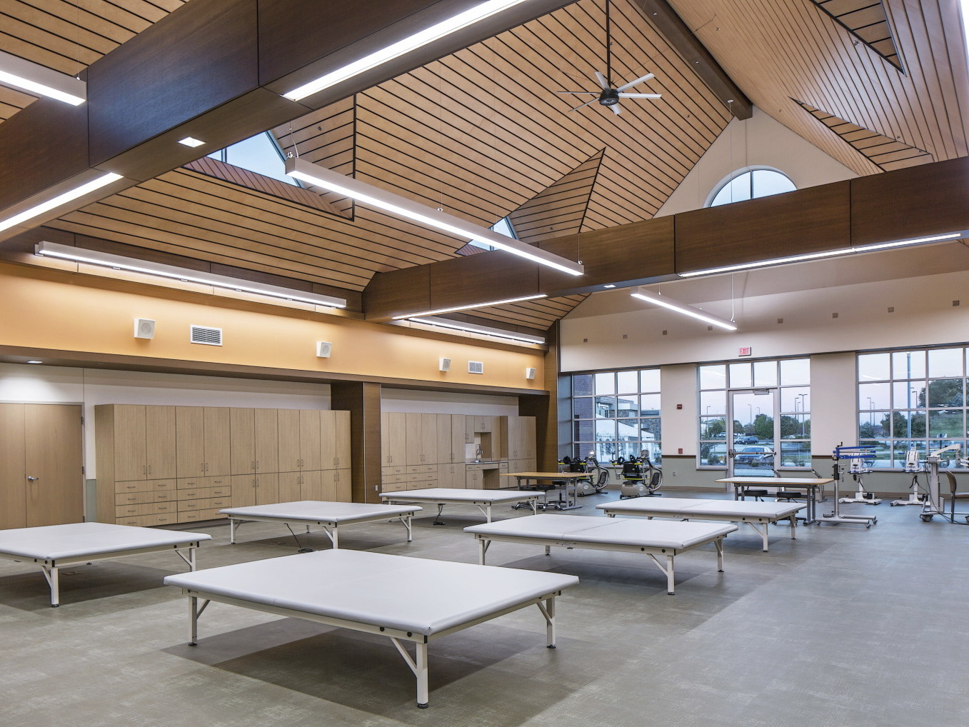 Room with wood paneled side ceilings coming to a point. Recessed triangular windows and wood trusses across width of room