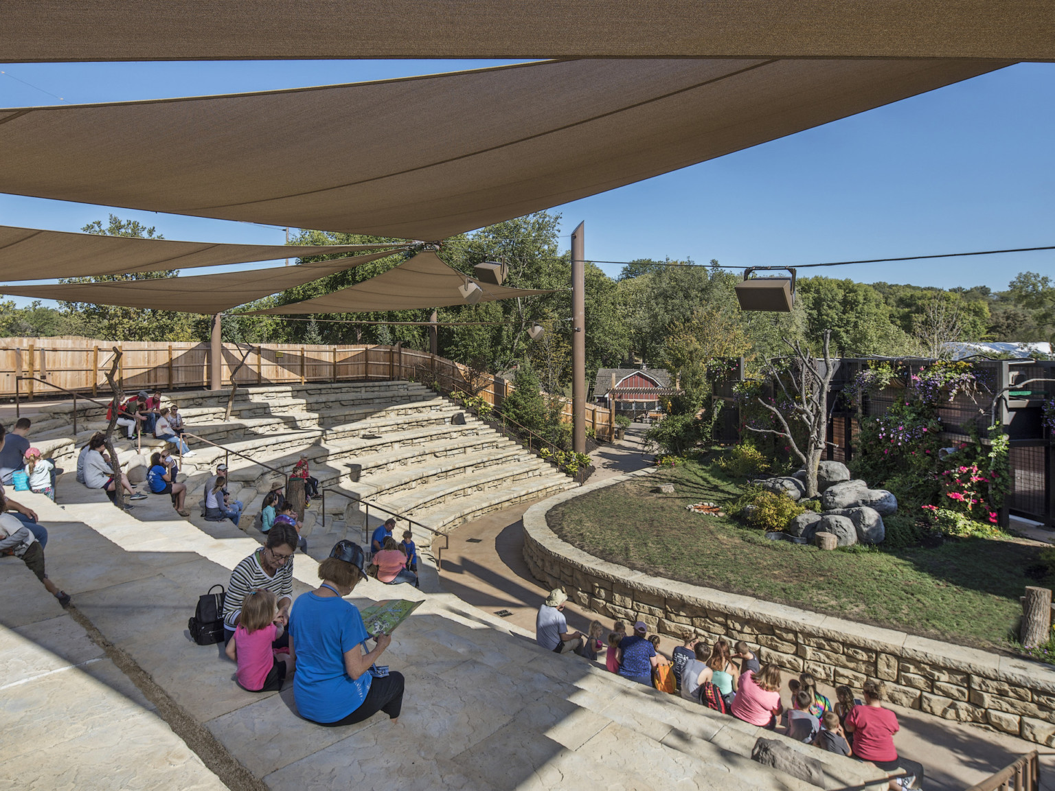 Partially covered organic rock bleacher seating curving to face stage with grass and trees