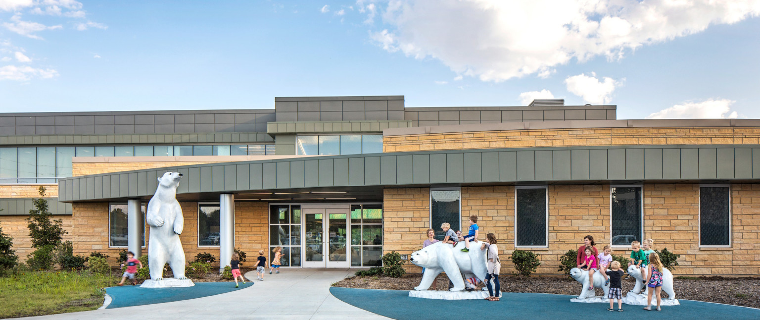 Exterior building entry framed by sculpture of 2 polar bears and 2 cubs surrounded by blue in ground padding