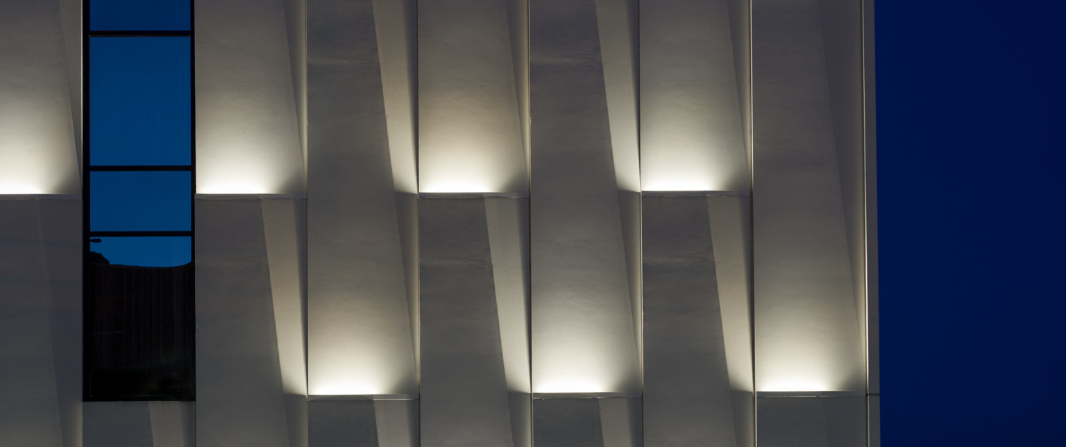 Panels in lifted wall grooves with recessed lighting illuminated at night