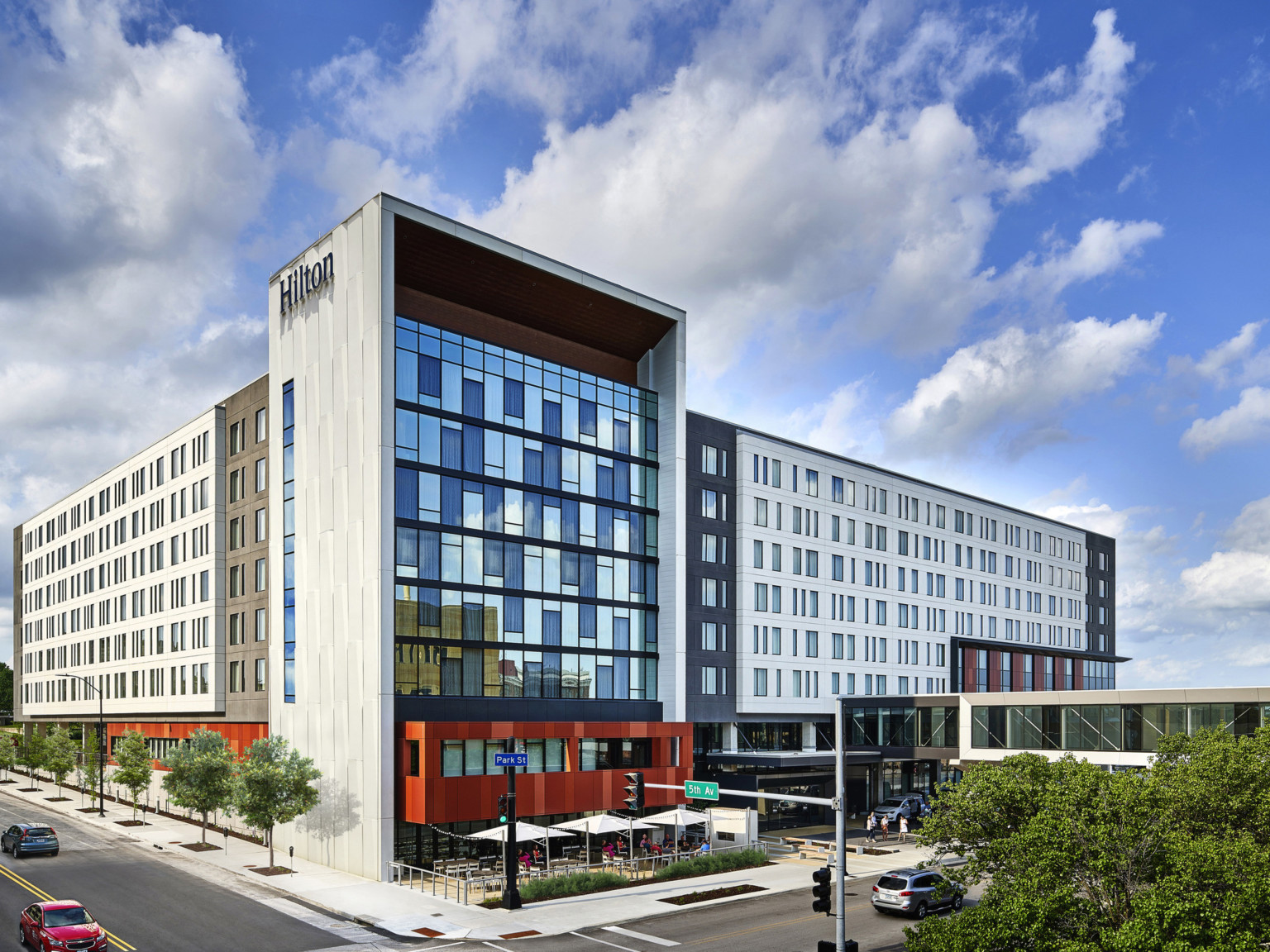 Hilton Des Moines Downtown hotel seen from the front corner. Window front wall shaded by extended white wall with Hilton sign