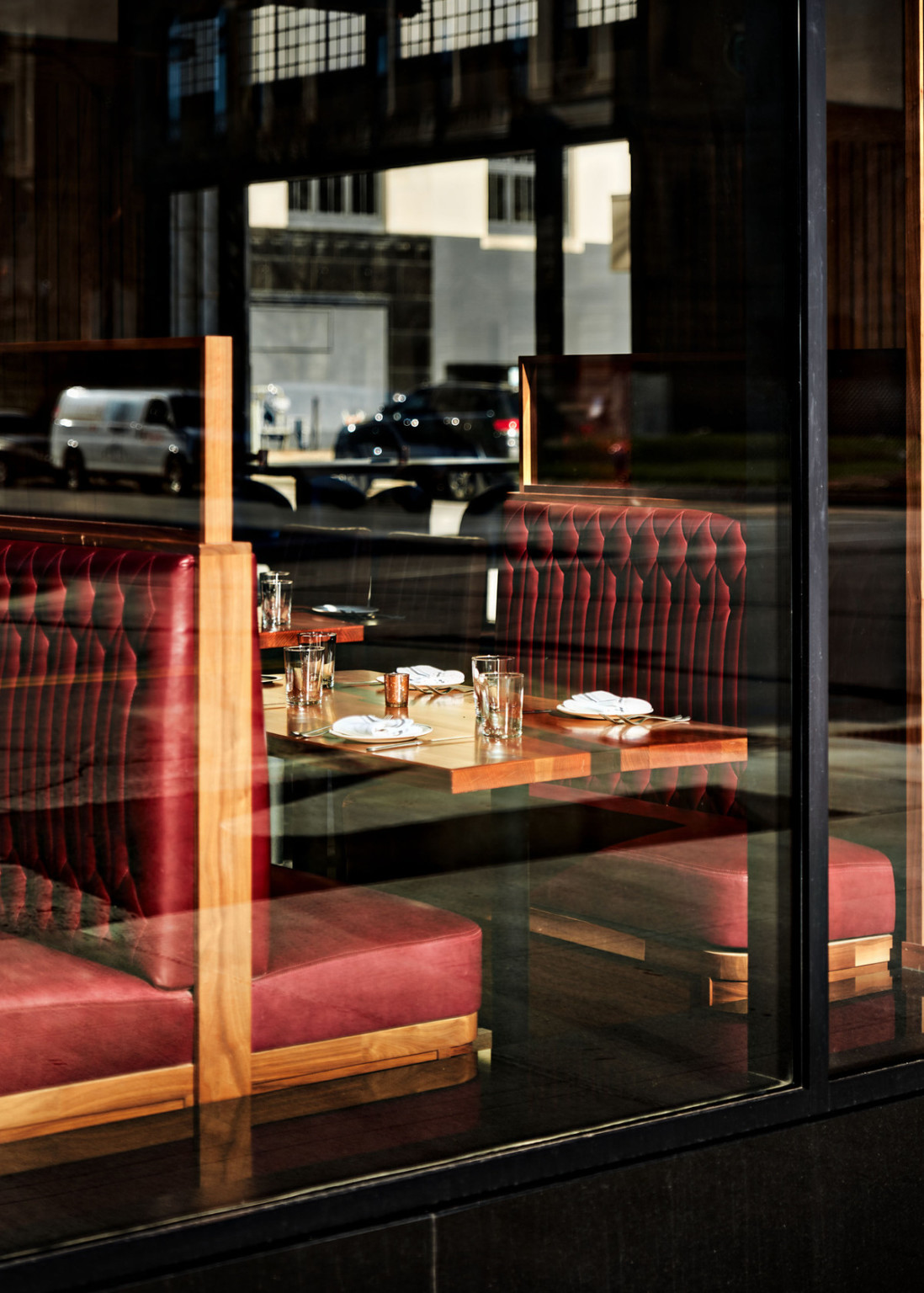 Red quilted booth with wood table seen from outside floor to ceiling window