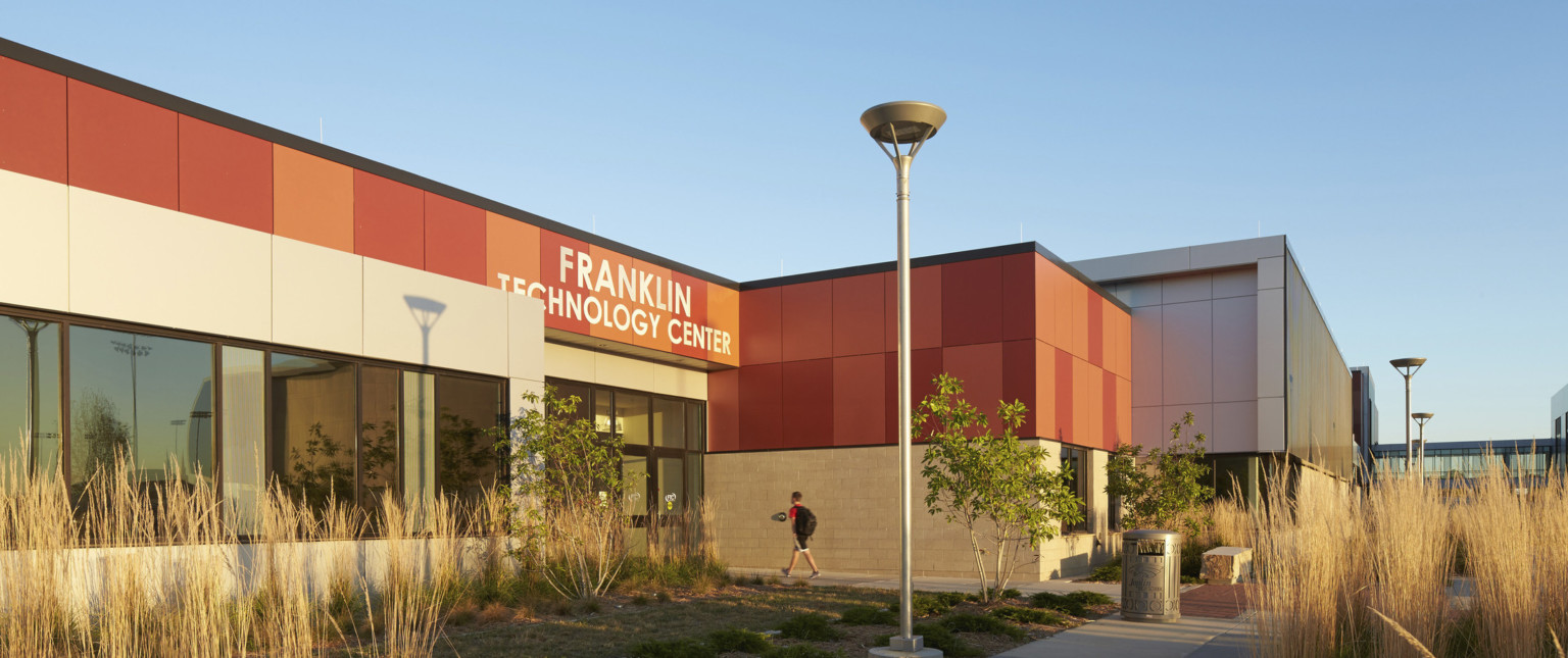 Stone base on 1 story building with orange panels. Building labeled Franklin Technology Center is surrounded by native plants