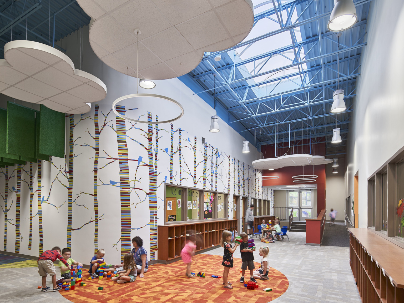 open ceiling with skylights and suspended acoustic panels in the shape of clouds with super graphics on the walls