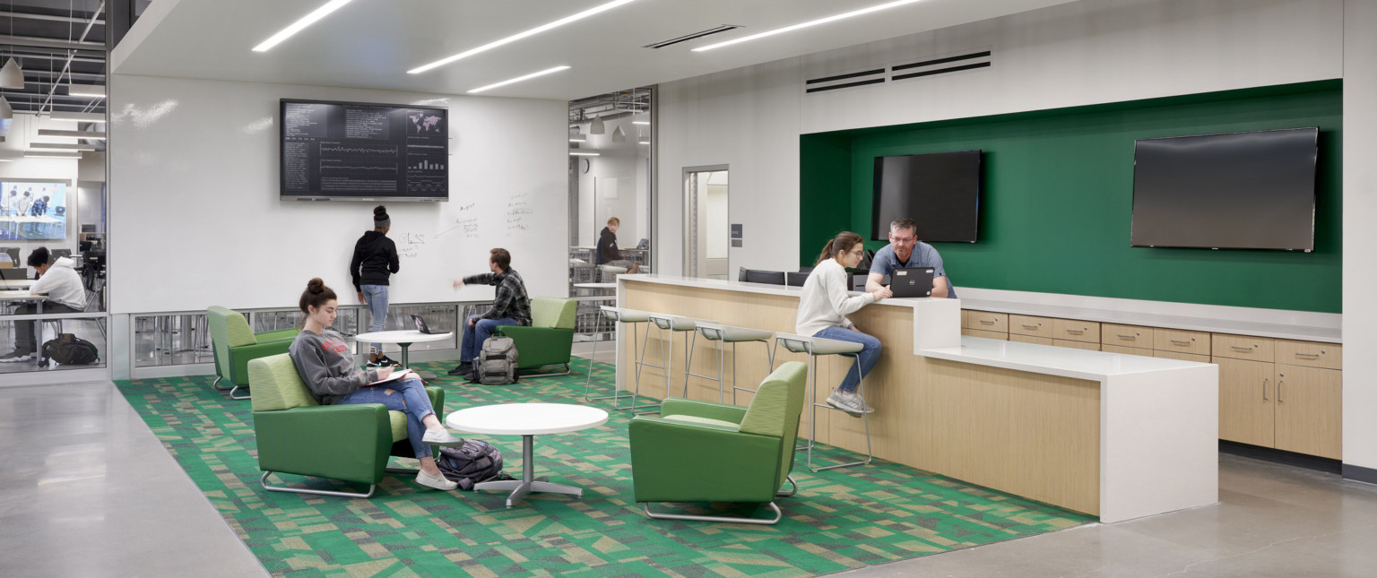 Room with white board wall and recessed light bars. Island and seating area. Green recessed wall detail, right, over counter