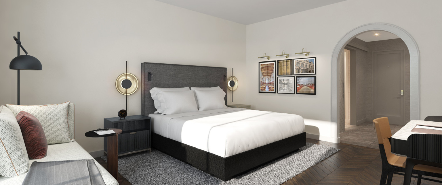 View of guest room facing hall, past bed with dark wood base, grey headboard with reading lights, and large round lamps