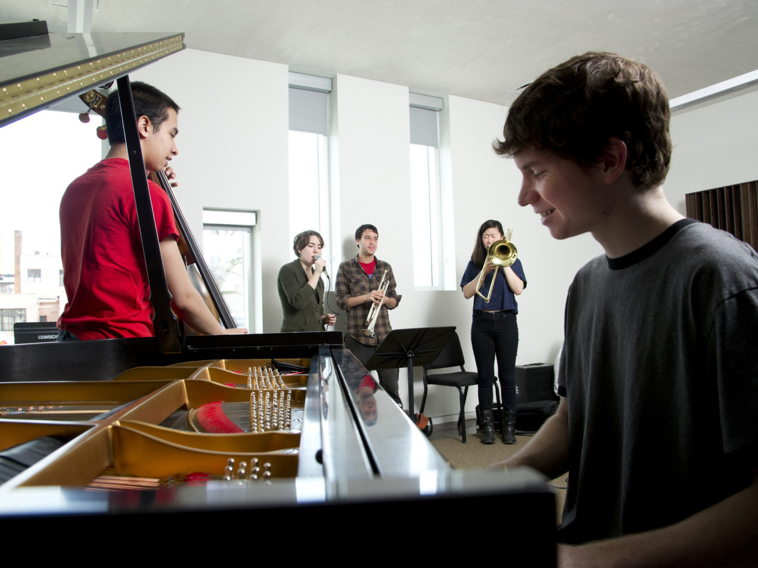 Musicians play in white room with 4 tall, thin rectangular windows with light coming through