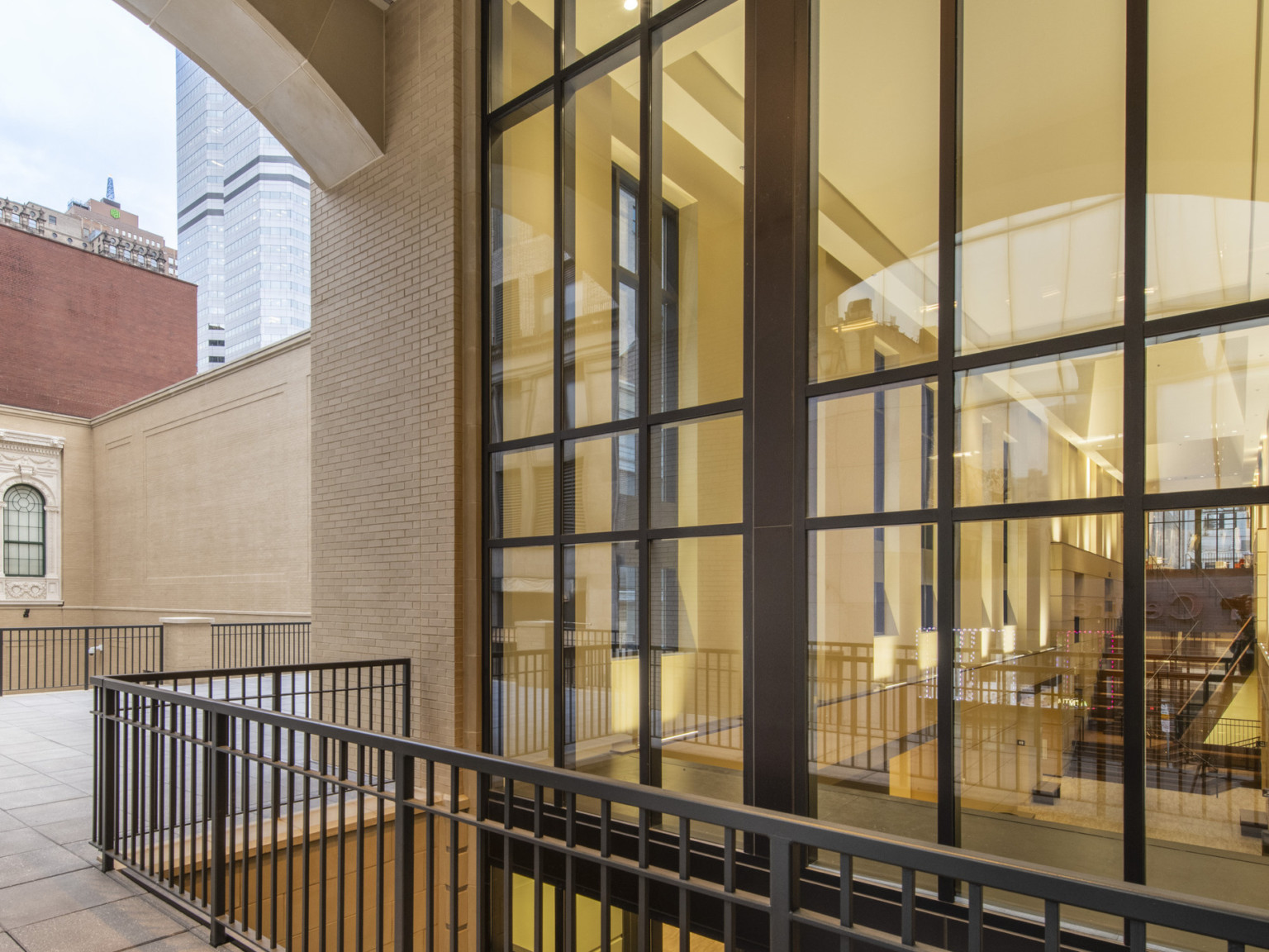 Exterior view from walkway under and arch with obscured view into window. In the background outside are city views