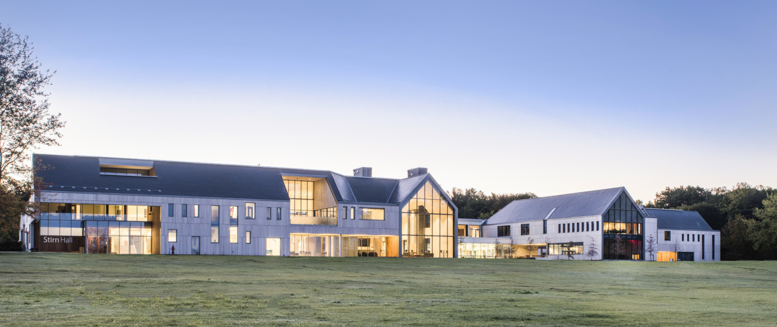 Exterior view from lawn of building labeled Stirn Hall. Sections of recessed window in a grey 3 story building