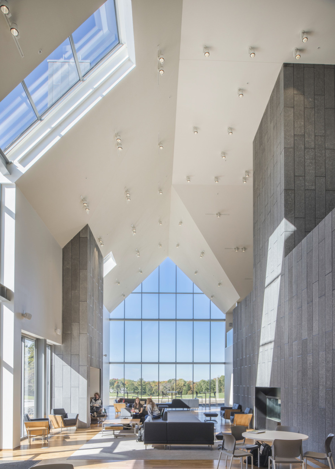 White cathedral ceiling with stone accent walls. Double height pointed window at end. Window wraps around angle of side wall