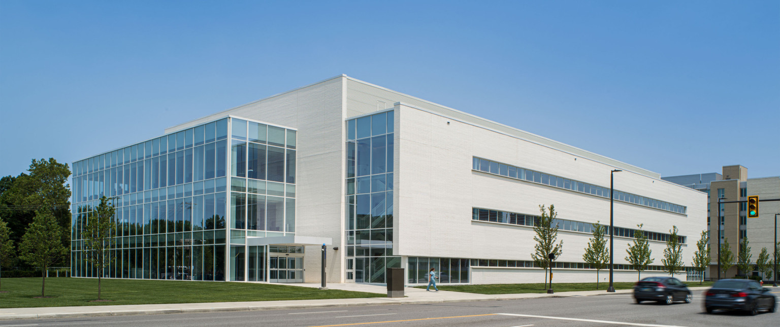 White stone and glass building seen at corner from across the street. Upper levels of right wall are stone, the rest windows