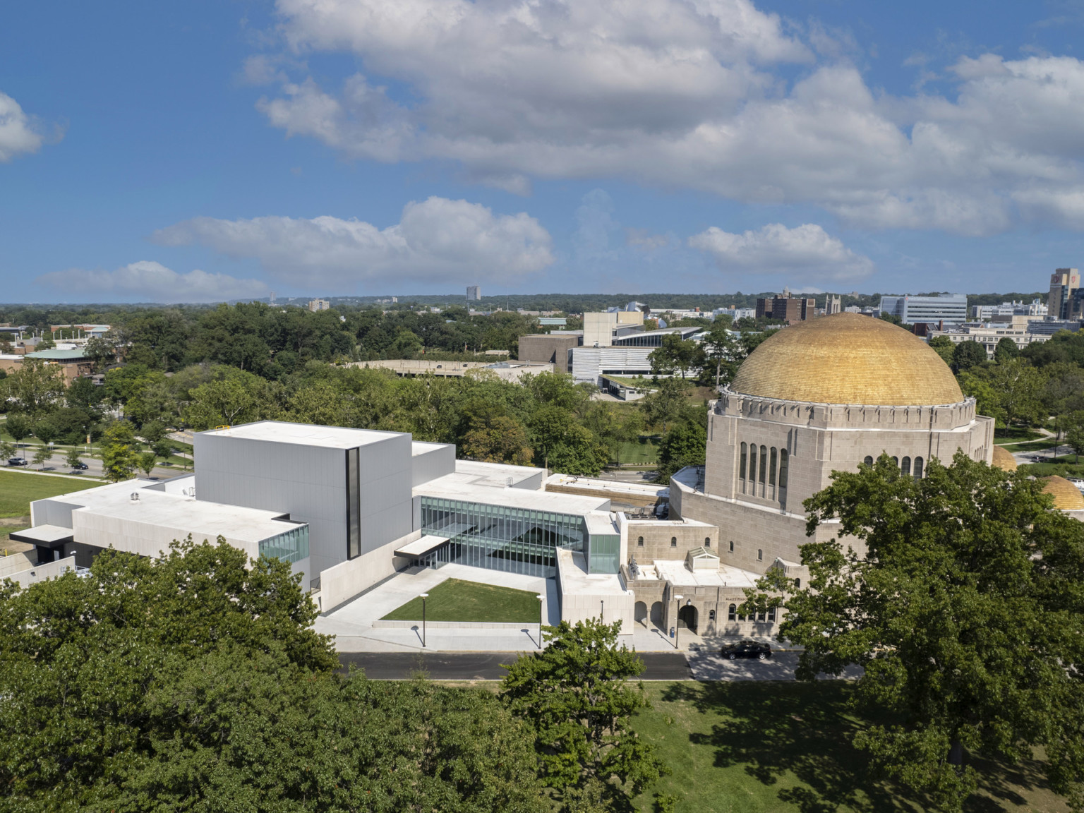 View from above of glass building connecting modern concrete building to historic building with yellow dome