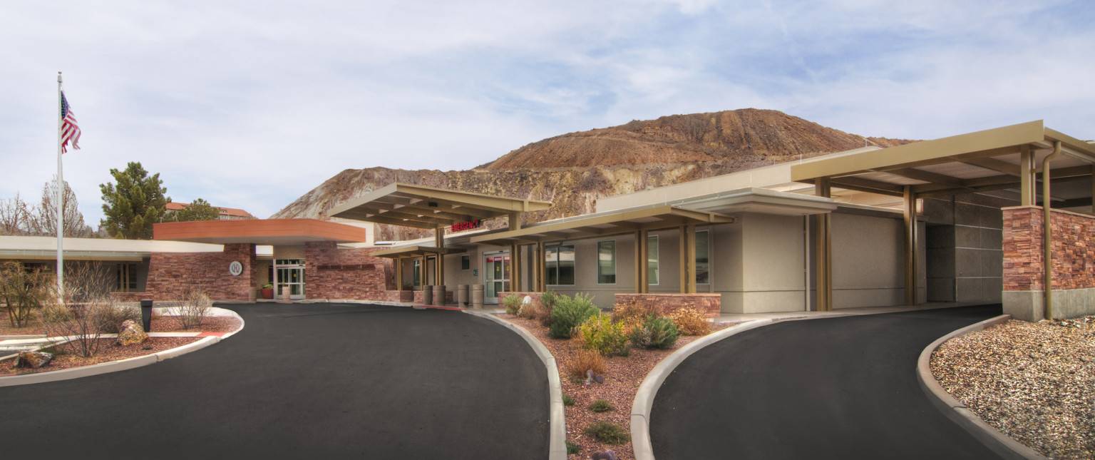 Exterior view from between 2 driveways of the Copper Queen Community Hospital front entrances in front of mountain